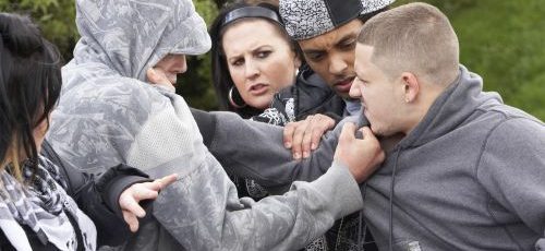 Groep jongeren waarbij 2 jongens elkaar agressief vastgrijpen