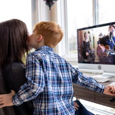 Moeder en kind voor computer op de rug gezien, kind kust moeder op de wang