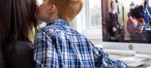 Moeder en kind voor computer op de rug gezien, kind kust moeder op de wang