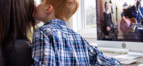 Moeder en kind voor computer op de rug gezien, kind kust moeder op de wang